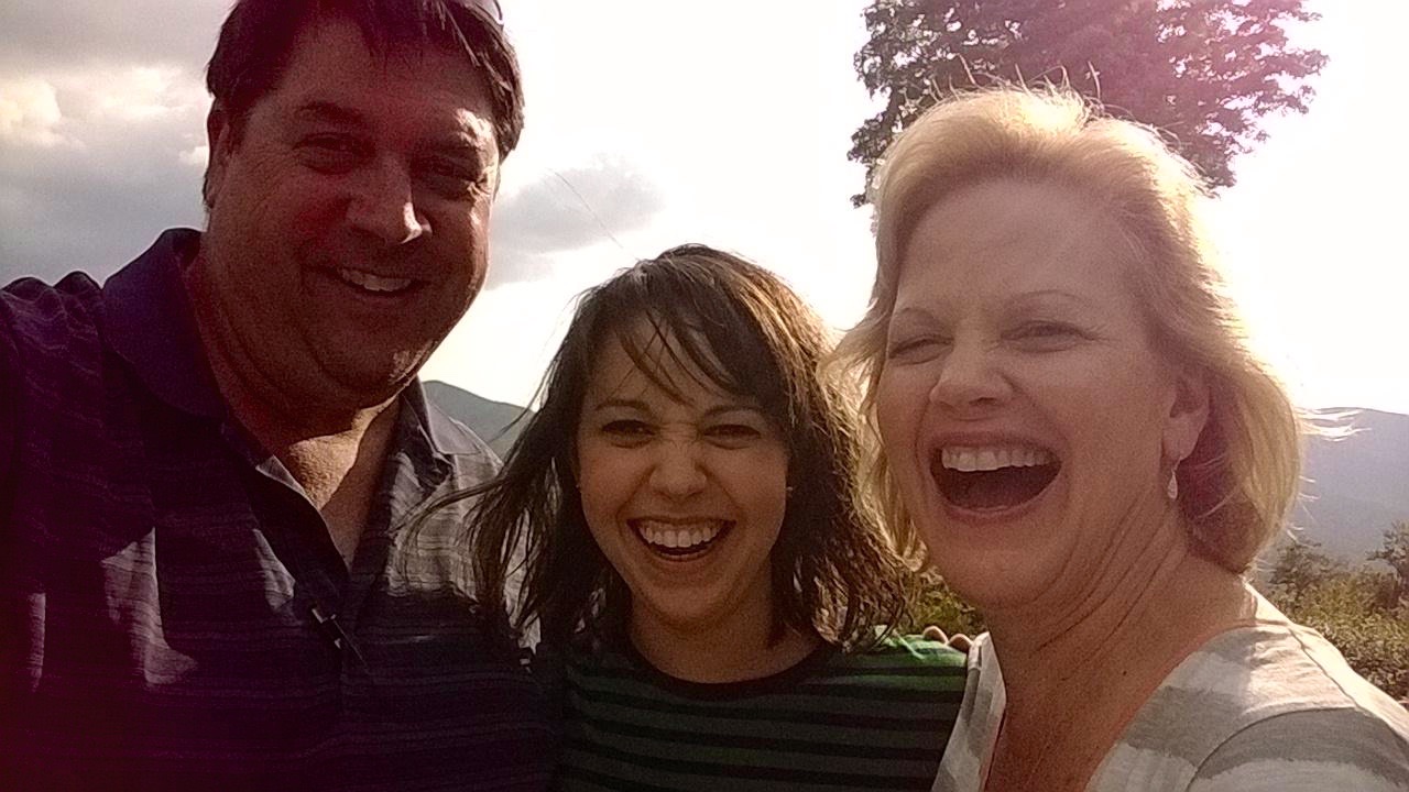 Todd smiling in a bright family selfie with Caren and one of their daughters.