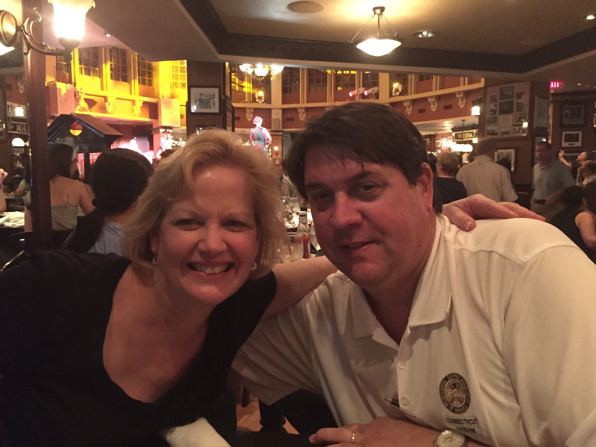 Todd and Caren smiling together during a night out at a lively restaurant.